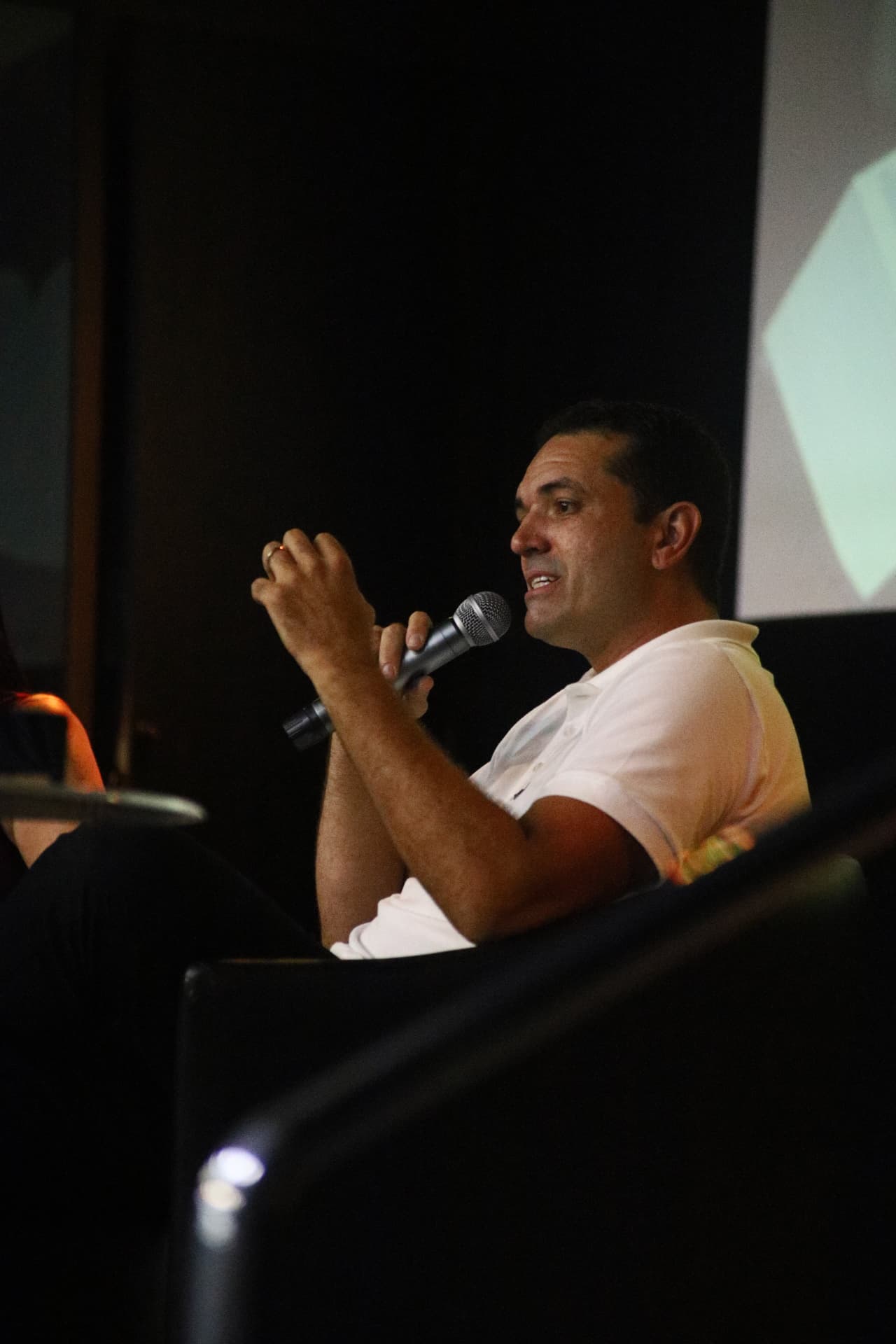 Douglas Campos falando ao microfone em um painel